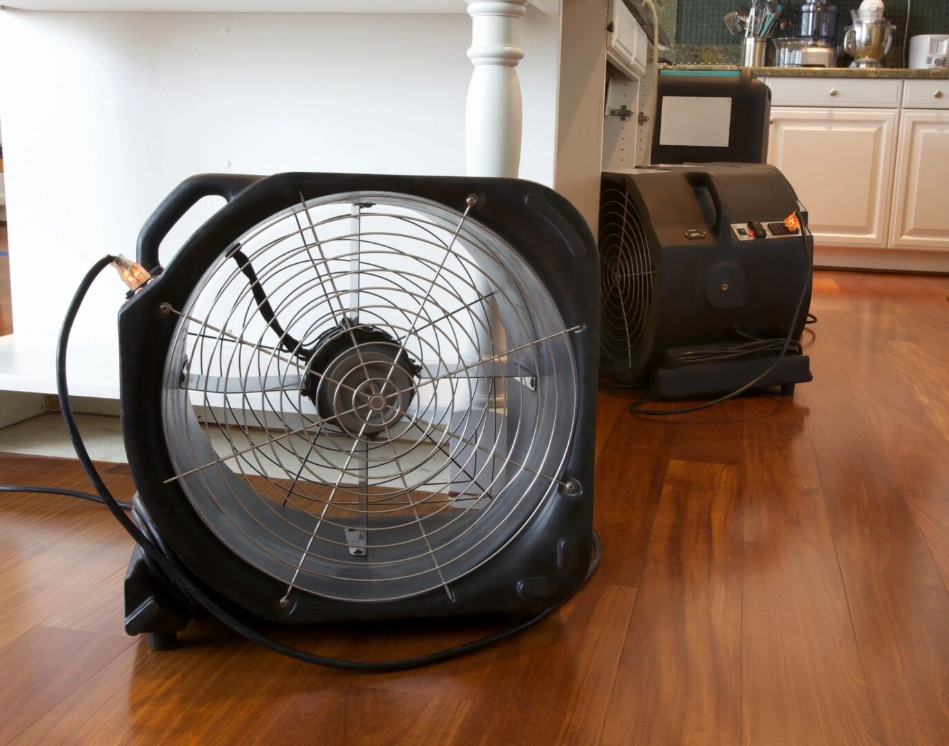 A fan is sitting on the floor next to an air conditioner.