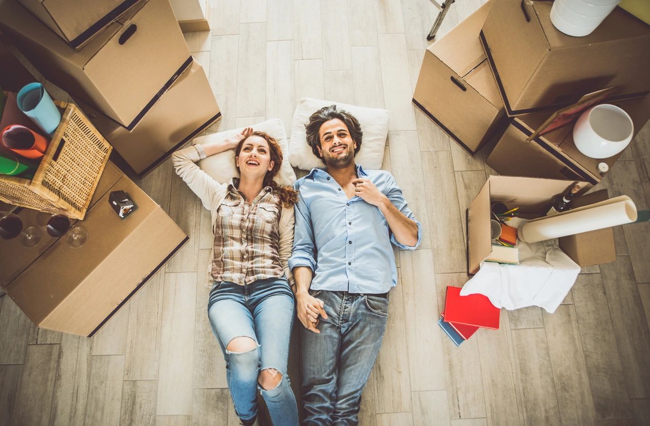 A man and woman laying on the floor in front of boxes.